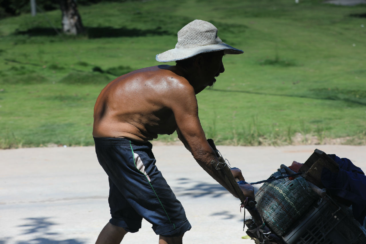 駝背的老人推著小車(chē)賣(mài)菜